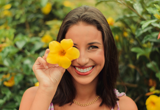 Self-awareness transformation. A woman happily holds a yellow flower, radiating joy and warmth with her smile.